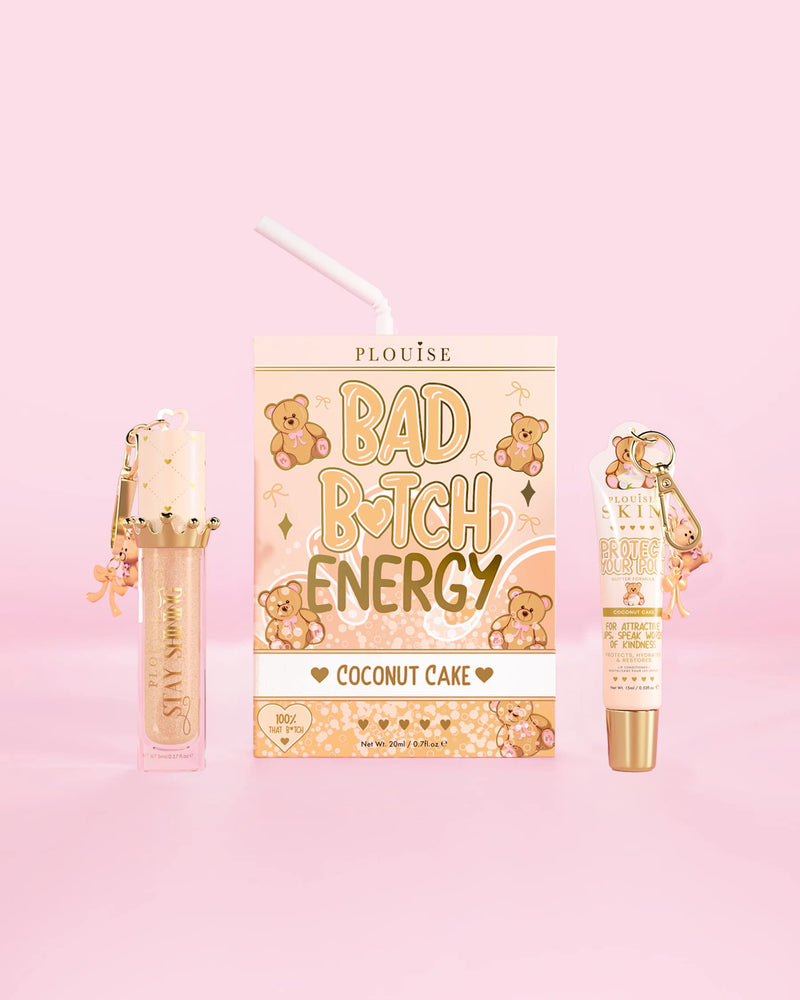 Ein P.Louise Teddy Glitter Bad Bitch Energy Lip Duo mit Kokosnusskuchen-Duft, einer Lippenpflege und einem Lippenöl vor einem rosa Hintergrund