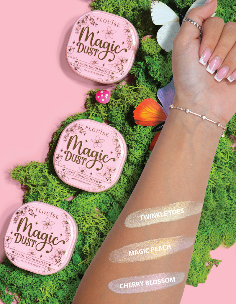 Drei kompakte, lose Textmarker mit der Aufschrift „Magic Dust“ in den Farbtönen Twinkle Toes, Magic Peach und Cherry Blossom, präsentiert auf einem Arm mit floralem Hintergrund.