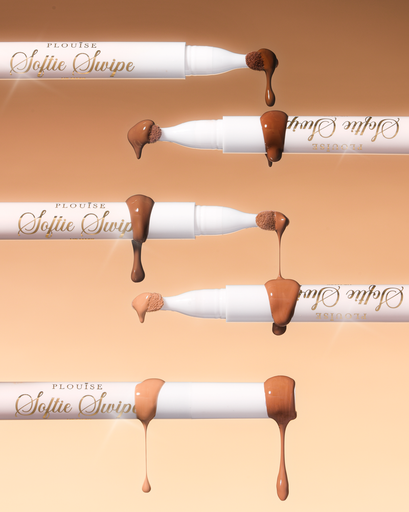 Ein Bild von fünf P.Louise Softie Swipe Tinted Lip Masks mit aus den Spitzen tropfendem Produkt, das die verschiedenen Farbtöne vor einem beigen Hintergrund zeigt