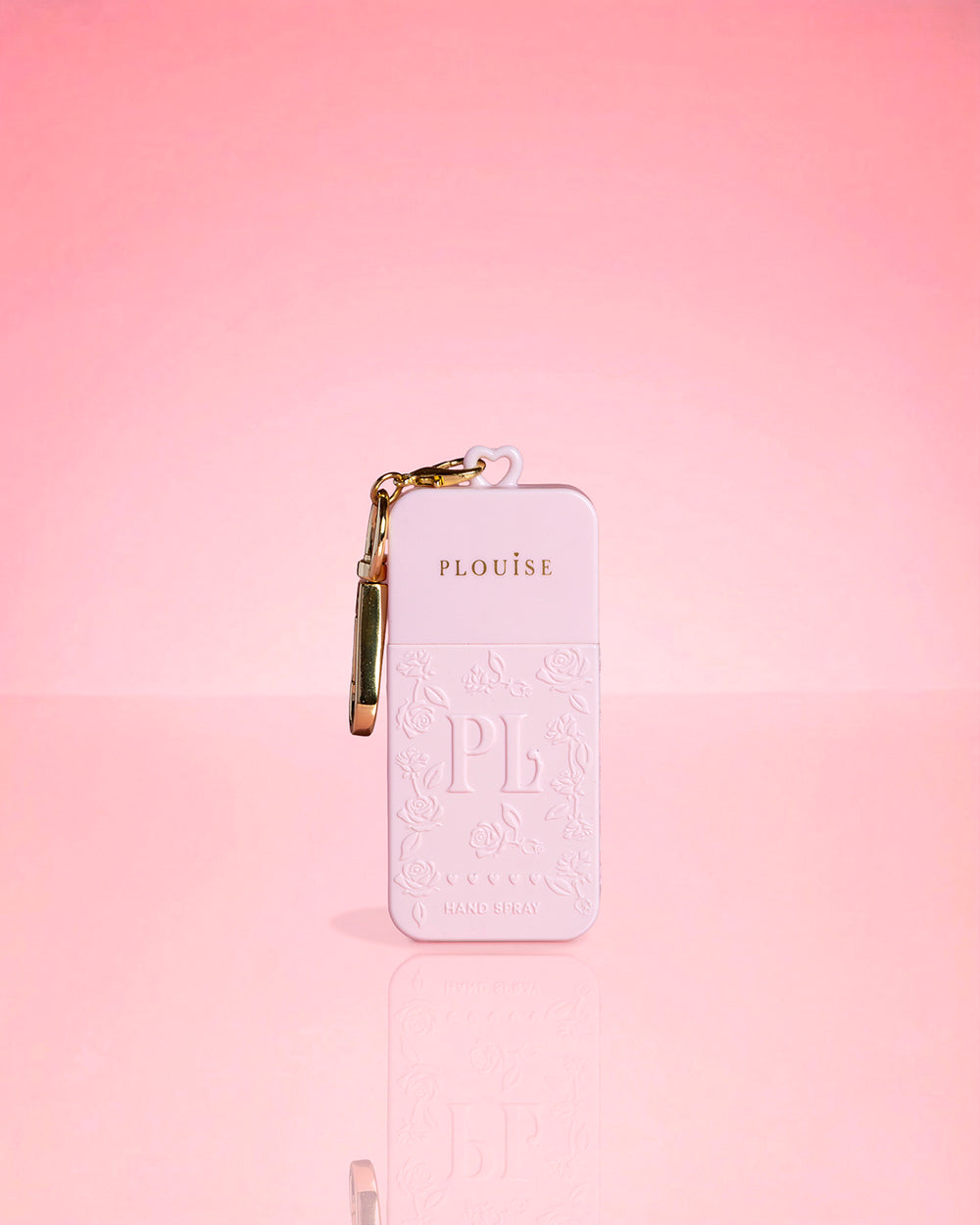 Pink bottle of P.Louise Hand Sanitiser Spray in signature scent with gold keychain on a pink background