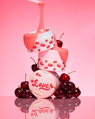 3 tubs on top of each other of the P. Louise Peel The Love Peel Off Facial surrounded by cherries on a pink background