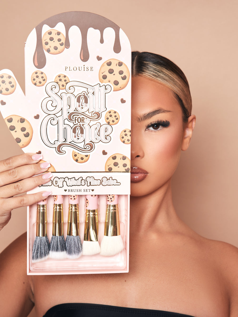 Ein Bild des 5-teiligen Make-up-Pinselsets „Spoiled For Choice“ von P.Louise in einer Ofenhandschuh-Verpackung mit einem herausgezogenen Tablett an der Unterseite, das die Pinsel teilweise zeigt. Auf der Verpackung ist das halbe Gesicht eines Models mit Make-up zu sehen