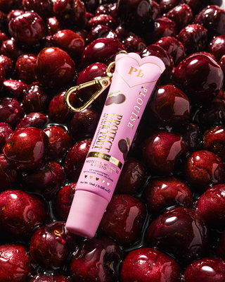 Pink black cherry scented tinted protect your pout lip conditioner with gold clip on a bed of cherries