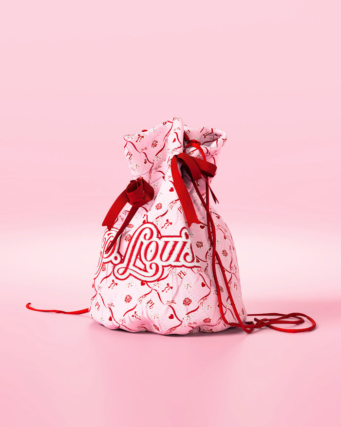 Rosa Kordelzugtasche mit roten Schleifen und festlichem Design mit „P.Louis“-Branding auf rosa Hintergrund