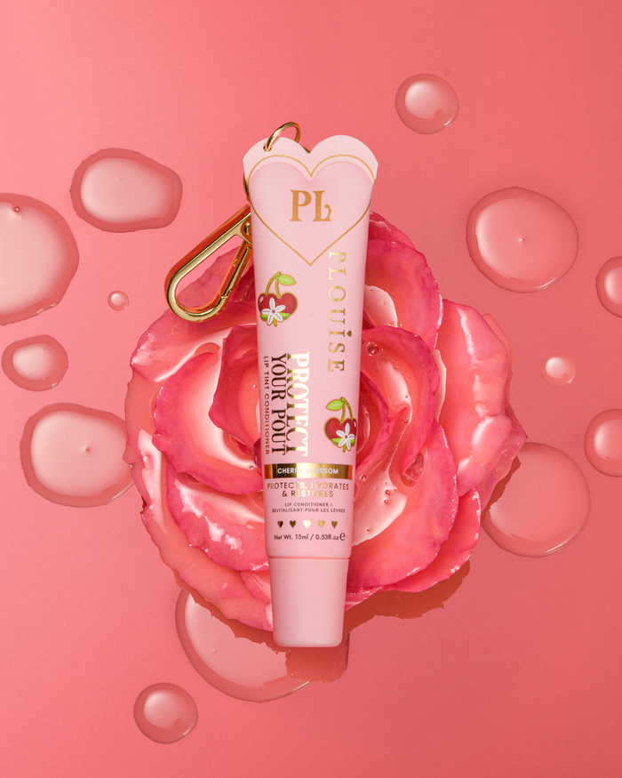 Eine getönte, nach rosa Kirschblüten duftende, schützende Lippenspülung mit goldenem Clip auf einer rosa Blume