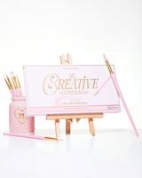 Eine geschlossene rosa P.Louise Creative Comeback XXXL Rainbow-Lidschattenpalette auf einer Kunststaffelei, umgeben von Make-up-Pinseln