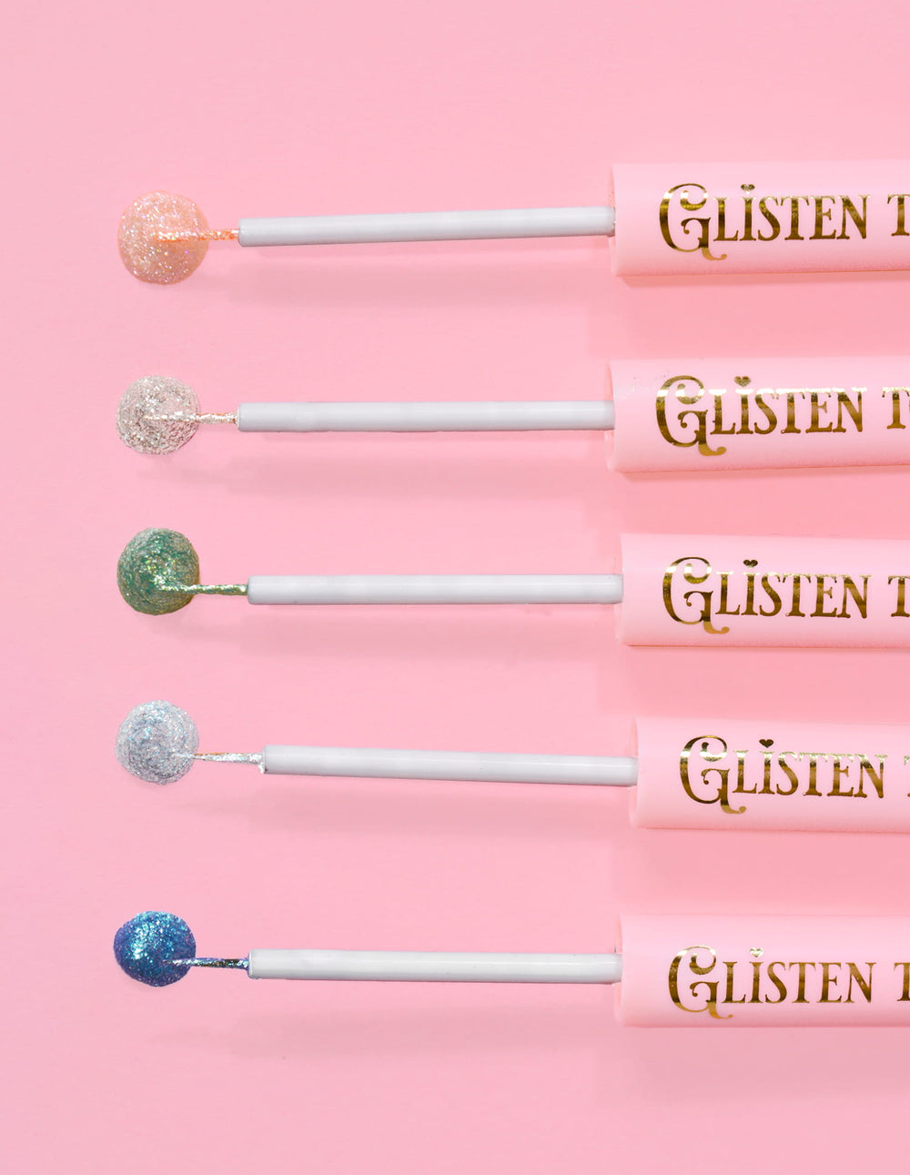 5 glitzernde Eyeliner von P.Louise Glisten To Your Heart in einer Reihe mit einem Tropfen Produkt am Ende vor einem rosa Hintergrund