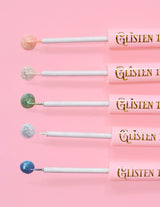 5 glitzernde Eyeliner von P.Louise Glisten To Your Heart in einer Reihe mit einem Tropfen Produkt am Ende vor einem rosa Hintergrund