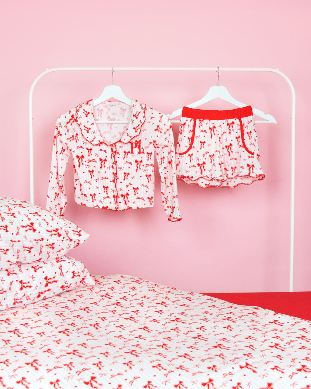 Rosa-weiß gestreifte Mädchen-Pyjamashorts von P.Louise mit Weihnachtsschleife auf Kleiderbügeln in einem rosafarbenen Schlafzimmer mit passender Bettwäsche 