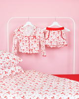 Rosa-weiß gestreifte Mädchen-Pyjamashorts von P.Louise mit Weihnachtsschleife auf Kleiderbügeln in einem rosafarbenen Schlafzimmer mit passender Bettwäsche 