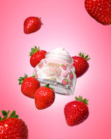 Glas mit P. Louise Soft-Eiscreme-Feuchtigkeitscreme, umgeben von Erdbeeren auf rosa Hintergrund