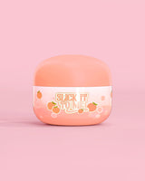 Glas mit P. Louise Slick It To Me Peach Melting Body Balm mit rosa Hintergrund