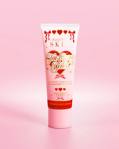 Rosafarbene Tube schimmernde Körpercreme „The Glow Down“ von P.Louise mit Kokosnussküstenduft vor rosa Hintergrund