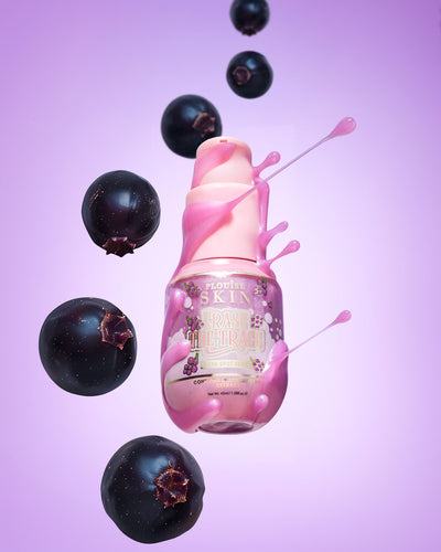 Rosa Flasche P. Louise Erase The Trace Dark Spot Correcting Serum mit aus der Flasche austretender Flüssigkeit, umgeben von schwarzen Johannisbeeren auf violettem Hintergrund