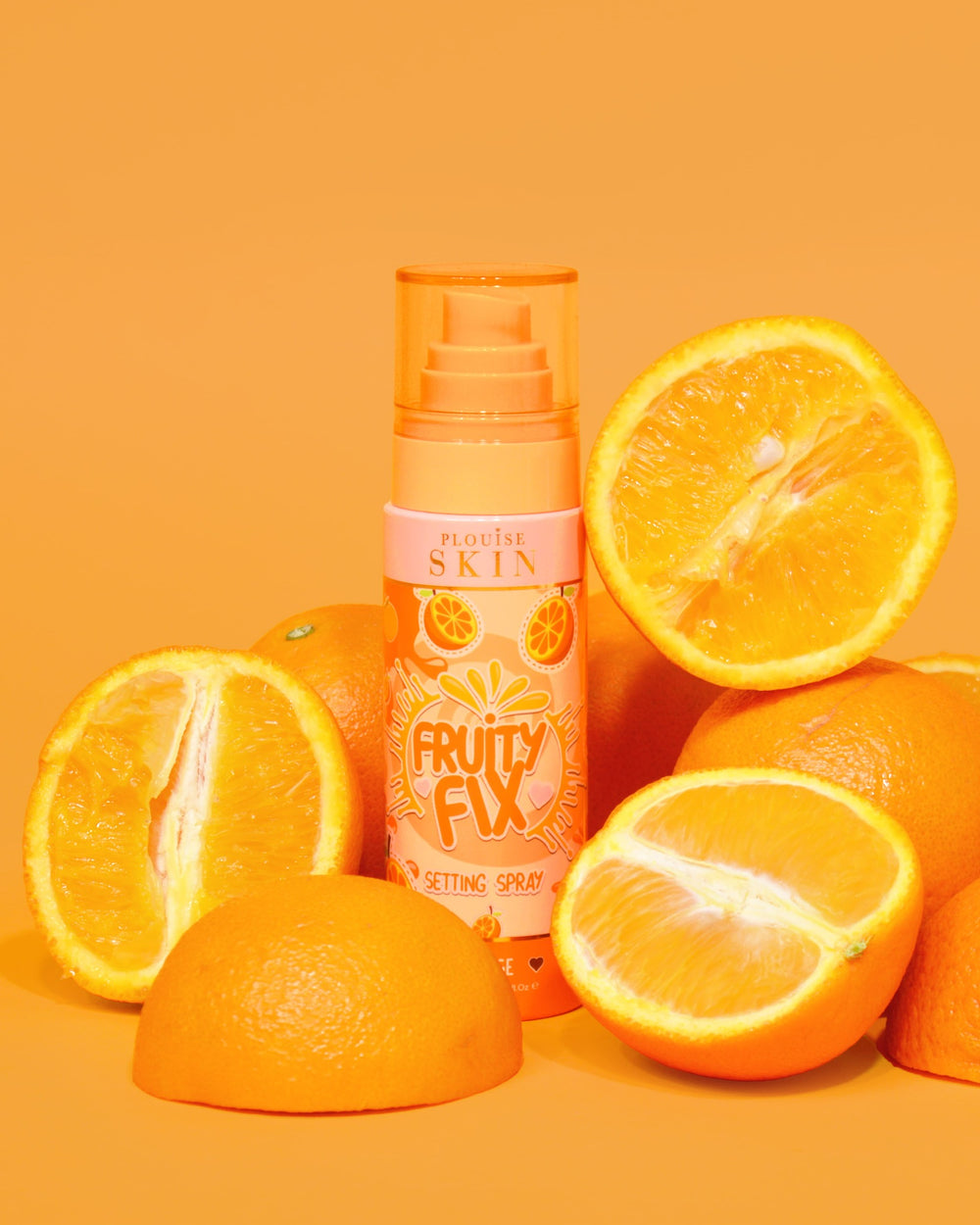 Eine orangefarbene Flasche P. Louise Fruity Fix Vitamin C Setting Spray mit orangefarbenem Hintergrund, umgeben von frischen Orangenscheiben.