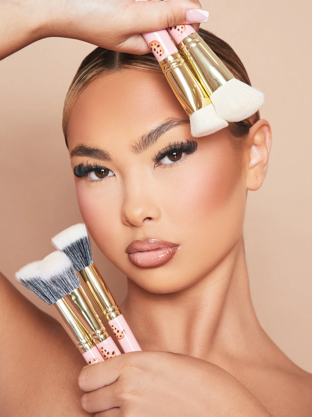 Ein Bild einer geschminkten Frau, die das 5-teilige Make-up-Pinselset „Spoiled For Choice“ von P.Louise gegen ihr Gesicht hält