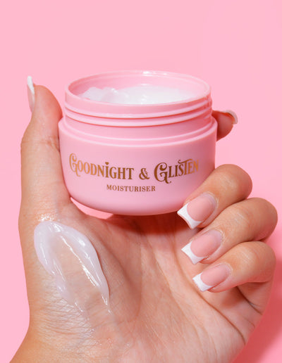 Eine Hand hält ein rosafarbenes Glas P.Louise Goodnight & Glisten Gel Moisturizer, auf dem etwas Feuchtigkeitscreme zu sehen ist